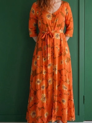 2-Piece Boho Set — Maxi Dress + Playsuit | L - lSnygg långklänning i orange med stora blommor i gult och grönt. Klänningen har trekvartsärm, v-ringning och ett knytband i midjan för en markerad siluett. Tillverkad i ett lätt och luftigt material, perfekt för varma dagar.