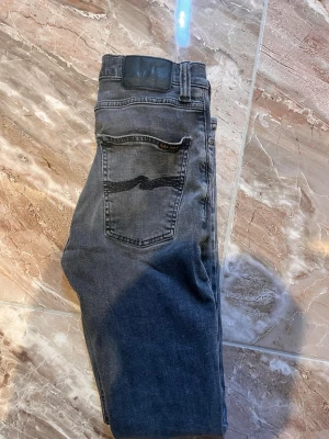 Nudie jeans - Säljer ett par snygga svarta nudie jeans i storlek 27/30, jeansen har inga hål eller defekter och är i bra skick. Tveka inte till att fråga minsta lilla och pris går att diskutera vid snabb affär!!