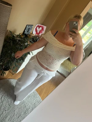 Vit offshoulder spets topp - Säljer en vit offshoulder topp i spets med genombrutet mönster. Toppen är ärmlös och har en bred kant över axlarna som ger en snygg och trendig look. Perfekt för dig som vill ha en feminin och somrig stil.
