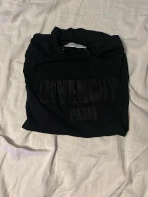 Svart Givenchy t-shirt med tryck - Snygg svart t-shirt från Givenchy med stort tryck på bröstet där det står 'GIVENCHY PARIS'. Klassisk passform och rund halsringning, perfekt för en stilren och trendig look.