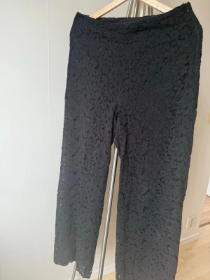 Svarta leggings med spetsmönster - Säljer ett par svarta leggings med blommigt spetsmönster. De har en rak och något lösare passform än klassiska leggings och är tillverkade i ett stretchigt material som ger en unik look. Perfekta för dig som vill sticka ut lite extra.
