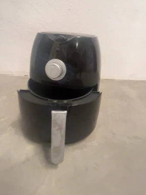 Svart airfryer med silverdetaljer - Säljer en svart airfryer med silverfärgad ratt och handtag. Maskinen har en rund form och en utdragbar korg för enkel tillagning av mat utan olja. Perfekt för dig som vill laga mat snabbt och smidigt hemma.
