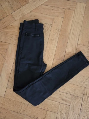 SOM NYA Byxa stl 34 från Nelly i matt skinnimmitation  - SOM NYA Byxa ser ut som en matt skinnimmitation/ strech Matt yta Från Nelly Stl 34 Innerbenslängd ca 71 cm Grenhöjd ca 27 xm Fickor med dragkedja fram Ej låg midja ANVÄNDA 1 G SUPER SNYGGA BYXOR