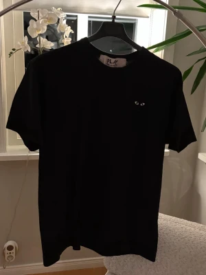Svart Comme des Garçons PLAY t-shirt - Säljer en svart t-shirt från Comme des Garçons PLAY. Köpt på nk för 899kr och har knappt använt den vilket gör att skicket är väldigt bra utan några defekter. Säljer för 299kr.