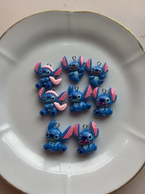 Blå Stitch-berlocker  - Säljer flera söta berlocker formade som Stitch från Lilo & Stitch. De blå och rosa med små metallöglor för att enkelt fästa i halsband, armband eller nyckelringar. Perfekt för dig som gillar unika och söta accessoarer!😄