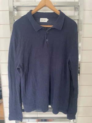 Mörkblå långärmad skjorta East West - Mörkblå långärmad skjorta från East West med klassisk krage och knappar framtill. Skjortan har en mjuk och lite texturerad yta som ger en avslappnad känsla. Perfekt för dig som gillar stilrena och enkla plagg.