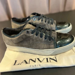 Lanvins - Snygga sneakers från Lanvin i brun mocka med mörka lackdetaljer på tån och svarta skosnören. Skorna har en vit sula och klassisk låg profil. Perfekta för dig som vill ha en stilren och exklusiv look.