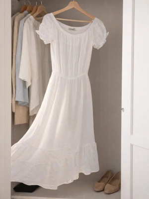 Vit långklänning med puffärmar. Storlek M. - Romantisk vit långklänning med volangkant och puffiga kortärmar. Klänningen har en smickrande, lös passform och är tillverkad i ett lätt bomullstyg. Perfekt för varma dagar och somriga tillfällen.
