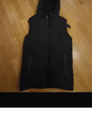 Svart dunväst med huva - Snygg svart dunväst med huva passar mellan 165-180 snygg clean och inga defekter storlek s men passar m också ingen aning märke 