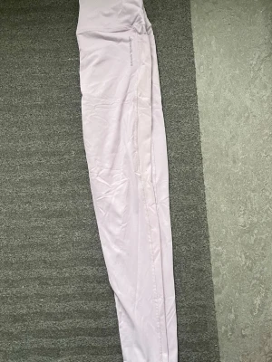 Ljuslila seamless leggings Aim'n - Supersnygga ljuslila seamless leggings från Aim'n med hög midja och stretchigt material. Perfekta för träning eller chill, med diskret logga på höften och smickrande passform. Materialet är mjukt och följsamt för maximal komfort.