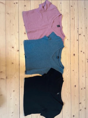 3-pack croppade toppar - Säljer tre croppade toppar, en i ljusrosa, en i blå och en i svart. Alla har v-ringning och korta ärmar, perfekta till jeans eller kjol. Superenkla att matcha och riktigt sköna på sommaren.