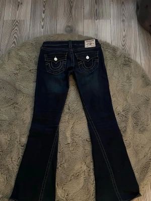 True religion jeans! - Säljer ett par jätte snygga True religion jeans i modellen Joey low rise flare och i storlek W26. Midjemått: 37cm, innerbenslängd: 80cm. Lite defekter längst ner på benet (syns på sista bilden). Annars är jeansen i bra skick💗