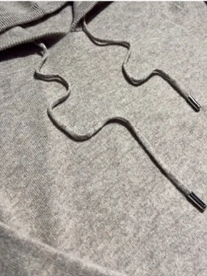 Kashmir hoodie - Stilren och supermjuk stickad hoodie i beige/ljusgrå nyans 🤍 Perfekt mix mellan avslappnat och minimalistiskt – funkar lika bra till vardags som till en mer uppklädd look. Skön passform, huva med snörning och ribbade muddar som ger en clean finish. Ett tidlöst plagg som passar året runt.  💭 Perfekt för dig som gillar neutral estetik och enkel stil.