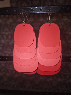 Örhängen från POW - Säljer ett par stora röda örhängen från POW, strl m. De har en modern och iögonfallande design som verkligen sticker ut. Perfekta för dig som vill ha något unikt och färgstarkt till din stil.