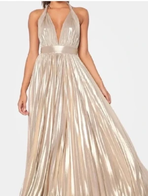 Champagnefärgad långklänning i satin - Elegant långklänning i glansig champagnefärgad satin med djup v-ringning och halterneck. Klänningen har markerad midja och ett vackert, plisserat fall som ger en lyxig känsla. Säljer även andra balklänningar så kolla min profil!.