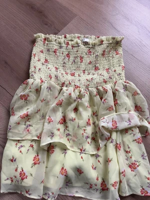 Gul blommig volangkjol - Supersöt kort kjol i ljusgul färg med blommigt mönster i rött och lila. Kjolen har smock i midjan och volangdetaljer som ger en luftig känsla. Perfekt för varma dagar och somriga outfits 💗💗