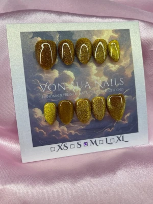 GoldenCateye (M);Extra Short Almond - Handgjorda press-on naglar i guldig , cateye färg med en kort mandelform. Naglarna har en snygg, skimrande cateye finish och levereras i storlek M: 16 mm, 12 mm, 12,5 mm, 11,5 mm, 10 mm. Perfekt för dig som vill ha en unik och trendig look.