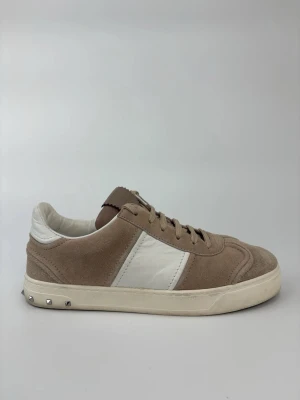 Valentino flycrew skor - Stilrena sneakers i beige mocka med vita läderdetaljer och vit sula. Snygga nitar på hälen ger en cool touch. Perfekta för dig som gillar en clean och trendig look. Skorna har klassisk snörning och låg profil.