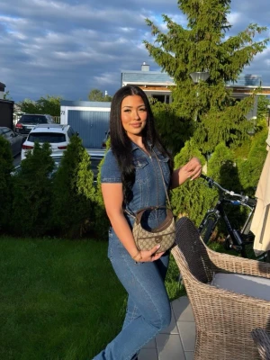 Blå jeansjumpsuit med dragkedja - Snygg blå jeansjumpsuit med korta ärmar och markerad midja. Jumpsuiten har dragkedja framtill, klassisk skjortkrage och fickor på bröstet. Materialet är stretchigt denim som ger en tight och bekväm passform. Perfekt för dig som vill ha en trendig och cool look.