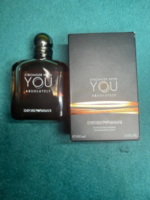 Emporio Armani Stronger With You Absolutely - Emporio Armani Stronger With You Absolutely är en elegant herrparfym i en mörkbrun glasflaska med silverfärgad kork. Flaskan har en stilren, fyrkantig form och rymmer 100 ml. Doften är intensiv och modern, perfekt för dig som gillar exklusiva parfymer.