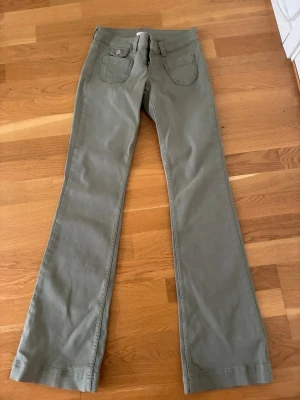 Olivgröna bootcut jeans från Nelly - Snygga olivgröna bootcut jeans från Nelly med klassiska fickor fram och bak. Jeansen har dragkedja och knapp i midjan samt breda hällor för bälte. Perfekta för dig som gillar en avslappnad men trendig stil.