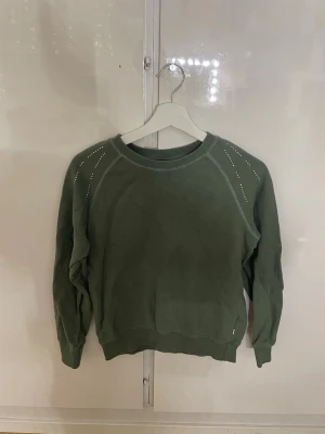 Mörk/olivgrön ridtröja med diamanter - Olivgrön ridtröja med rund halsringning och dekorativa stenar på axlarna. 