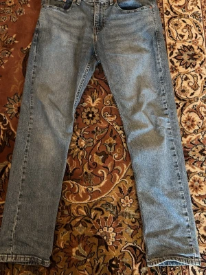 Levi's jeans - Säljer ett par blå Levis jeans i strl W29 och L30 med rak passform och normal midja. Jeansen har klassisk femficksdesign och är tillverkade i denim. Perfekta för en avslappnad och stilren look. De har används typ 2ggr. Säljer dem för 70kr då jag vill bli av med dem. Hör av er vid frågor!!
