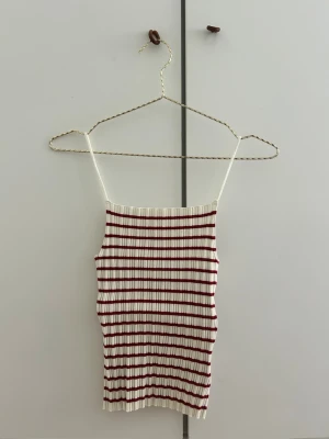 Randig ribbad linnetopp från H&M - Säljer en vit ribbad linnetopp från H&M med tunna axelband och röda horisontella ränder. Det är en stretchig material och passar alla som har storleken XS . Pris kan diskuteras 💕