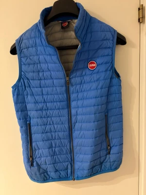 Blå dunväst från Colmar - Snygg blå dunväst från Colmar med quiltad design och dragkedja framtill. Västen har två praktiska fickor med dragkedja och en hög krage. Perfekt för lager-på-lager och har en sportig look med Colmar-logga på bröstet.