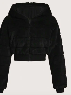 Svart croppad teddyjacka med huva - Mysig svart teddyjacka i croppad modell med dragkedja framtill och stor huva. Jackan har breda paneler och ribbade muddar vid ärmslut och midja. Perfekt för dig som vill ha en trendig och varm look. Tillverkad i mjukt, fluffigt material.