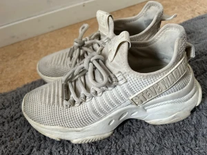 Vita Steve Madden sneakers - Chunky vita sneakers från Steve Madden med stickad mesh-ovandel och tjock sula. Skorna har snörning, dragflik bak och logga på sidan. Perfekta för en sportig och trendig look.