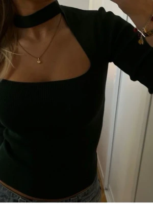 Svart ribbad topp med choker från Zara - Trendig svart ribbad topp från Zara med lång ärm och choker-detalj i halsen. Använd få gånger. 