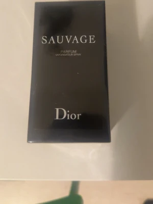 Dior Sauvage Parfum - Dior Sauvage Parfum i elegant svart förpackning med silverfärgade detaljer. Klassisk rektangulär kartong med tydlig Dior-logga och Sauvage-tryck. Parfymen är känd för sin fräscha och maskulina doft, perfekt för dig som vill sticka ut.