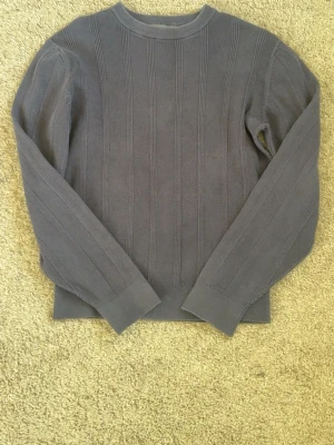 Dressmann tröja herr S blå bomull - Dressmann tröja för herr i storlek S. Färg blå/navy. Tillverkad i bomull. Rund halsringning och lång ärm. Stickad modell med diskret strukturmönster framtill och baktill. Passar som vardagströja eller som extra lager över t-shirt eller skjorta.