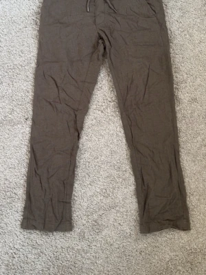 Dressmann byxor herr XS brun linneblandning - Dressmann byxor för herr i storlek XS. Byxorna är bruna och tillverkade i en linneblandning enligt tvättrådslappen. Modellen har resår i midjan med dragsko och raka ben. Passar som vardags- eller fritidsbyxor under varmare säsonger. Materialet ger en lätt och luftig känsla vid användning.