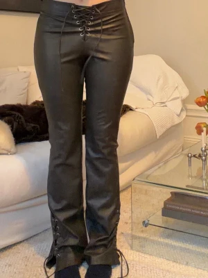 Läderbyxor med snörning  - Läderbyxor med snörning både fram i midjan och nertill vid bensluten. Dragkedja på sidan och snörning som justerar passformen i midjan samt om du vill ha de bootcut eller mer rakt. Storlek M, fint skick 🖤