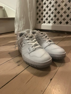  New Balance 550 sneakers - Säljer ett par vita New Balance 550 sneakers med klassisk, snygg retrodesign. Skorna har lågt skaft, vita skosnören och detaljer i läder. Perfekta för dig som gillar stilrena och tidlösa sneakers med en sportig vibe. Skorna är helt nya och knappt använda. Storlek 38,5. Skriv vid minsta fundering!🤩