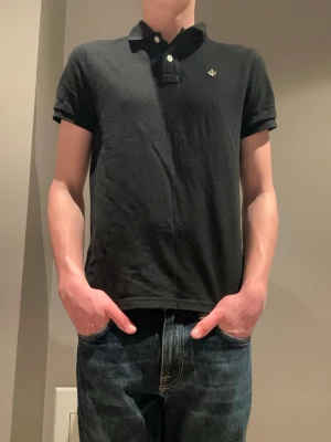 Morris piké - Klassisk svart pikétröja från Morris med korta ärmar och liten logga på bröstet. Tröjan har krage och knappar framtill. Perfekt till jeans eller shorts för en clean och enkel stil. Pikén är endast använd ett tiotal gånger vilket betyder att den är i mycket fin skick