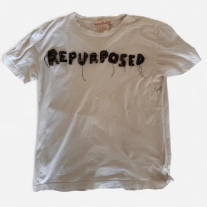 Vit t-shirt Acne Studios med text - Vit t-shirt från Acne Studios med svart broderad text 'REPURPOSED' framtill. T-shirten har rund hals och korta ärmar. Unik detalj med synliga trådar i brodyren som ger en kreativ och edgy look. Vintage köpt på deras flag store. Vad jag vet finns endas detta exemplar