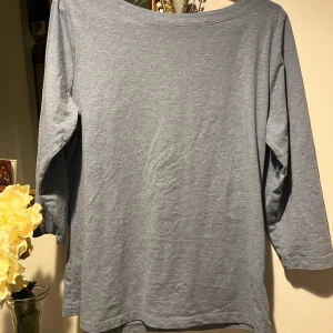 Blå topp med trekvartsärm från KappAhl - En enkel och snygg ljusblå topp från KappAhl, tillverkad i mjuk ekologisk bomull. Modellen har trekvartsärmar och en rund halsringning, perfekt för dig som gillar basic och bekvämt.