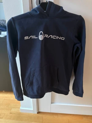 Mörkblå Sail Racing hoodie! - Bra skick! Använd ganska mycket men sparsamt använd! Storlek 160cm! Nypris ca 799 kr! Mitt pris 199 kr! Kan köpas med andra plagg som jag säljer för billigare pris! Tveka inte på att höra av er om ni har några funderingar! 