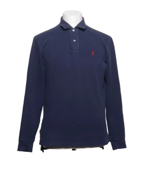 Mörkblå långärmad skjorta Polo Ralph Lauren - Klassisk mörkblå långärmad skjorta från Polo Ralph Lauren med krage och knappar framtill. Skjortan har en liten röd broderad logga på bröstet och är tillverkad i mjuk bomull. Perfekt för en clean och stilren look.