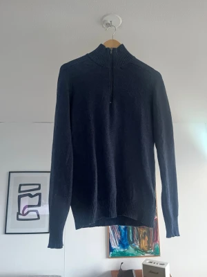 Mörkblå stickad half zip tröja - Mörkblå stickad tröja med half zip och hög krage. Tröjan har ribbade muddar vid ärmslut och nederkant, samt en relaxed passform. Perfekt för kyligare dagar och enkel att matcha med olika outfits. Tröjans storlek är S men sitter som en M.
