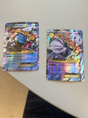 Pokémonkort MEGA Mewtwo EX & MEGA Blastoise EX - Två Pokémonkort: Mega Blastoise EX och Mega Mewtwo EX. Båda korten är holografiska med färgstarka och glittriga detaljer. Motiven visar Blastoise och Mewtwo i coola poser med japansk text och specialattacker. Perfekt för samlare eller Pokémonfans.