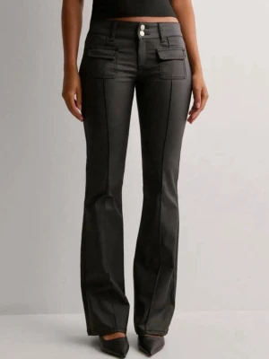 Svarta bootcut jeans med fickor - Snygga svarta bootcut jeans med hög midja och dekorativa fickor framtill. Jeansen har två silverfärgade knappar och markerade sömmar längs benen för en trendig look. Materialet ser ut att vara stretchigt och ger en smickrande passform.