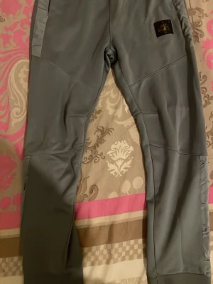 Grå Nike Air Max mjukisbyxor - Snygga grå mjukisbyxor från Nike Air Max med logga på benet. Byxorna har en modern, avsmalnande passform och är tillverkade i ett mjukt och bekvämt material. Perfekta för chill eller träning. Elastiska muddar vid benslut och diskret Nike-märke på sidan.