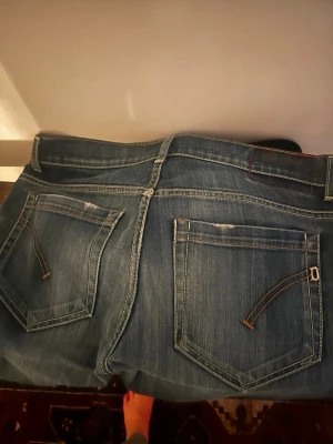 Blå jeans från Dondup  - Säljer ett par klassiska blå jeans från dondup med raka ben och snygga slitningar på bakfickorna. Perfekta till vardagslooken och tillverkade i slitstarkt denimtyg. Storlek 33 i Waist men är små i storleken som dondup är så sitter som 30-31