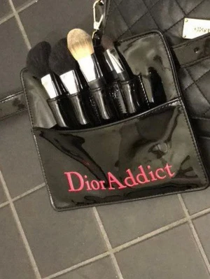 Svart sminkväska från Dior Addict - Snygg och elegant svart sminkväska från Dior Addict med plats för flera sminkprodukter. Väskan har en glansig finish och rosa text på framsidan. Perfekt för att organisera dina favoritprodukter när du är på språng!