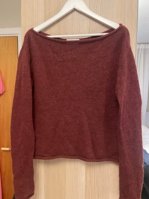 Vinröd stickad tröja Gina Tricot - Vinröd stickad tröja från Gina Tricot i ullblandning. Tröjan har en rak passform, långa ärmar och en bred, något båtformad halsringning. Perfekt för lager-på-lager och enkel att matcha med jeans eller kjol.