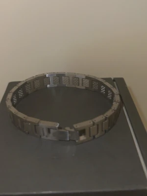 Stålarmband från Lacoste - Snyggt armband i rostfritt stål från Lacoste med länkdesign och graverad krokodil på spännet. Armbandet har en modern, maskulin känsla med detaljerade rutor och matt finish. Perfekt accessoar för att lyfta din stil.